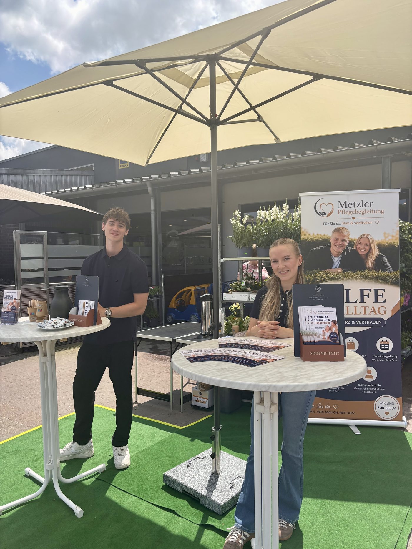 Yannick Diers und Isabel Schmal am Infostand von Metzler Pflegebegleitung vor EDEKA Inkoop in Stuhr-Moordeich